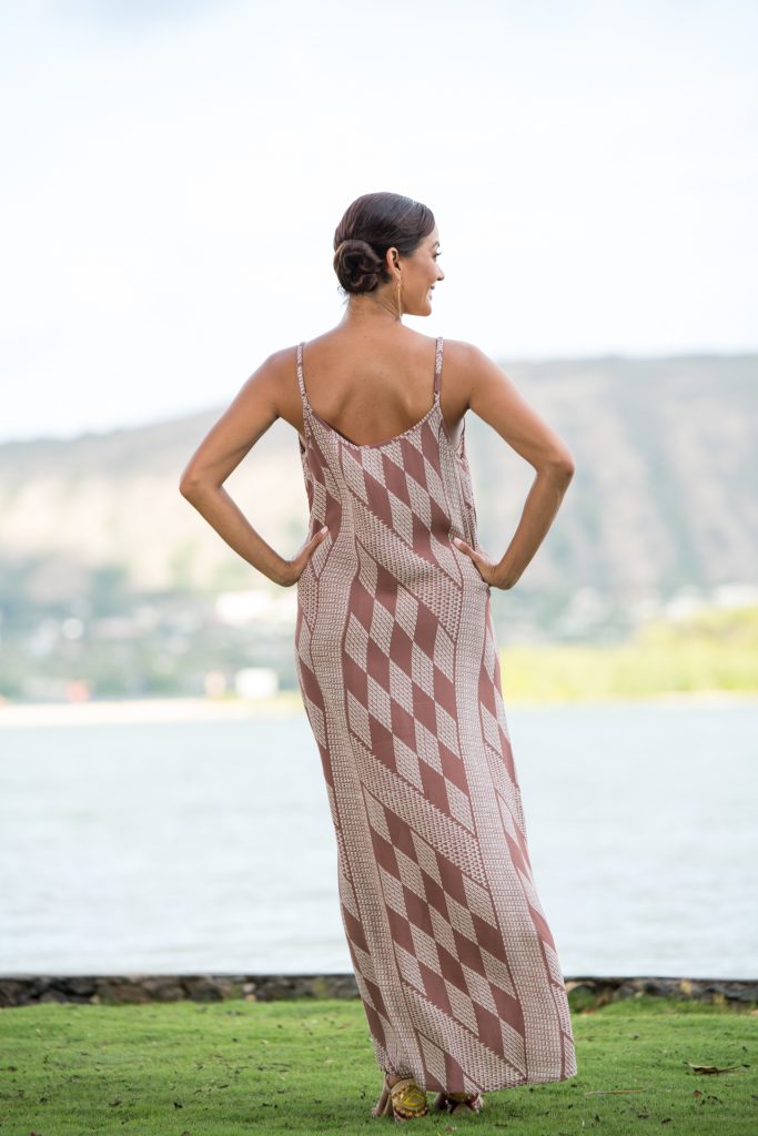 Model wearing Uluniu Maxi Dress in Fired Brick White Kamehameha Pattern - Back View