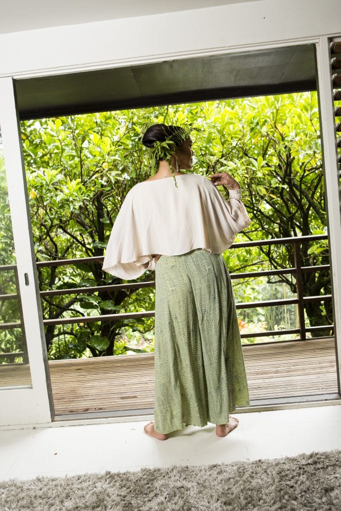 Female model wearing the tapa top in white and a skirt in sage green - Back View