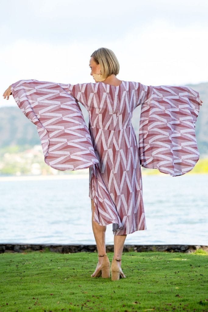 Female model wearing a Lilinoe Short Dress in Kanaloa Pattern and Fired Brick-White - Back View