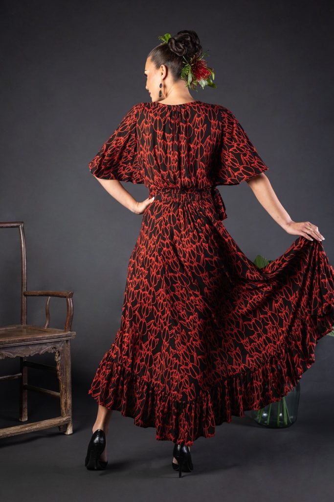 Female model wearing a Sepania Dress in Kapualiko Pattern and Black-Fiery Red - Back View