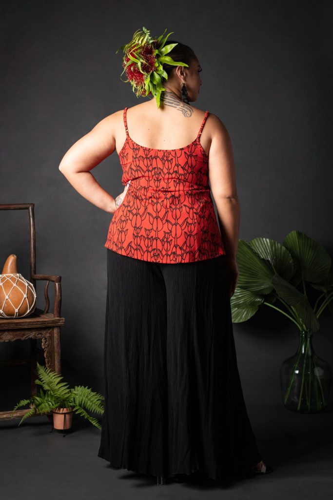 Female model wearing a Manaola Top 6 in a Kapualiko pattern and Fiery Red and Black Color - Back View