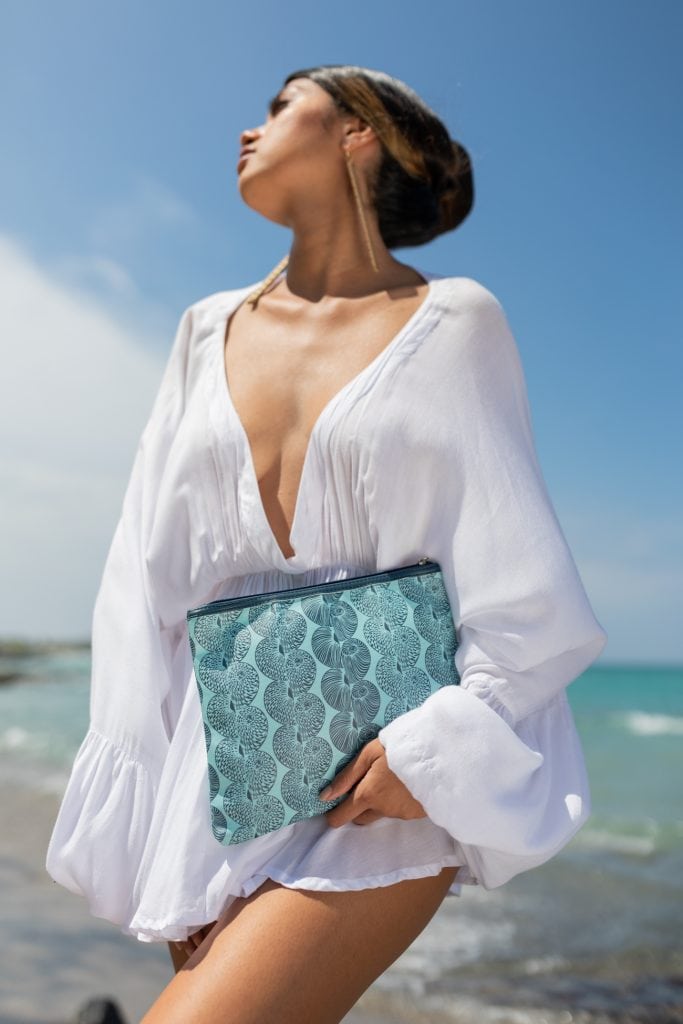 Female model holding a Flat Zip in a Lei Kupee Print and Blue Tint/Real Teal Color