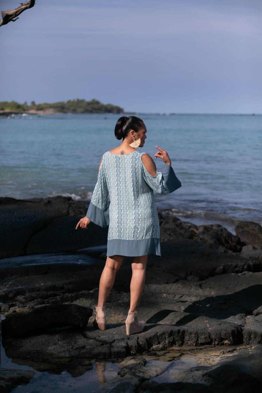 Female model wearing Kamakana Top w/ Pockets in a Lei Kupee Print and Blue Tint/Real Teal Color - Back View
