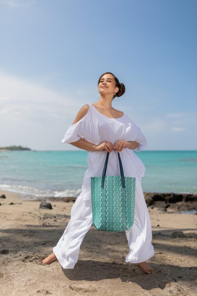Female model holding a Kanake Tote in a Lei Kupee Print and Blue Tint/Real Teal Color