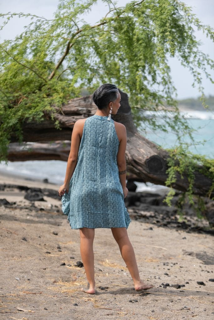 Female model wearing Kanoe Dress in a Lei Kupee Print and Real Teal/Blue Tint Color - Back View