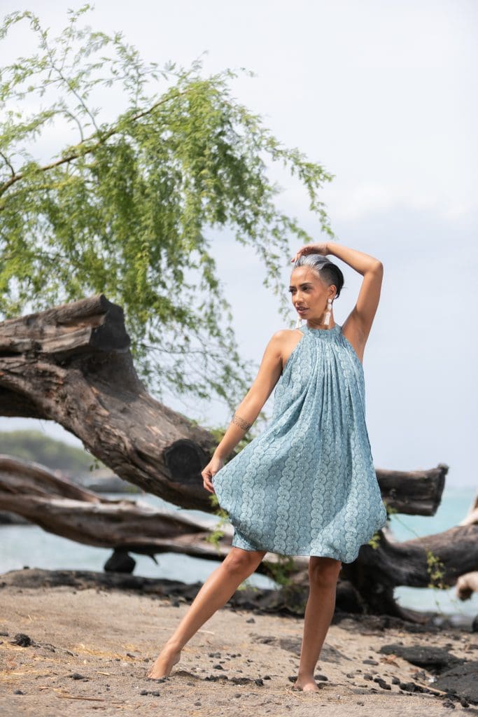 Female model wearing Kanoe Dress in a Lei Kupee Print and Real Teal/Blue Tint Color - Front View