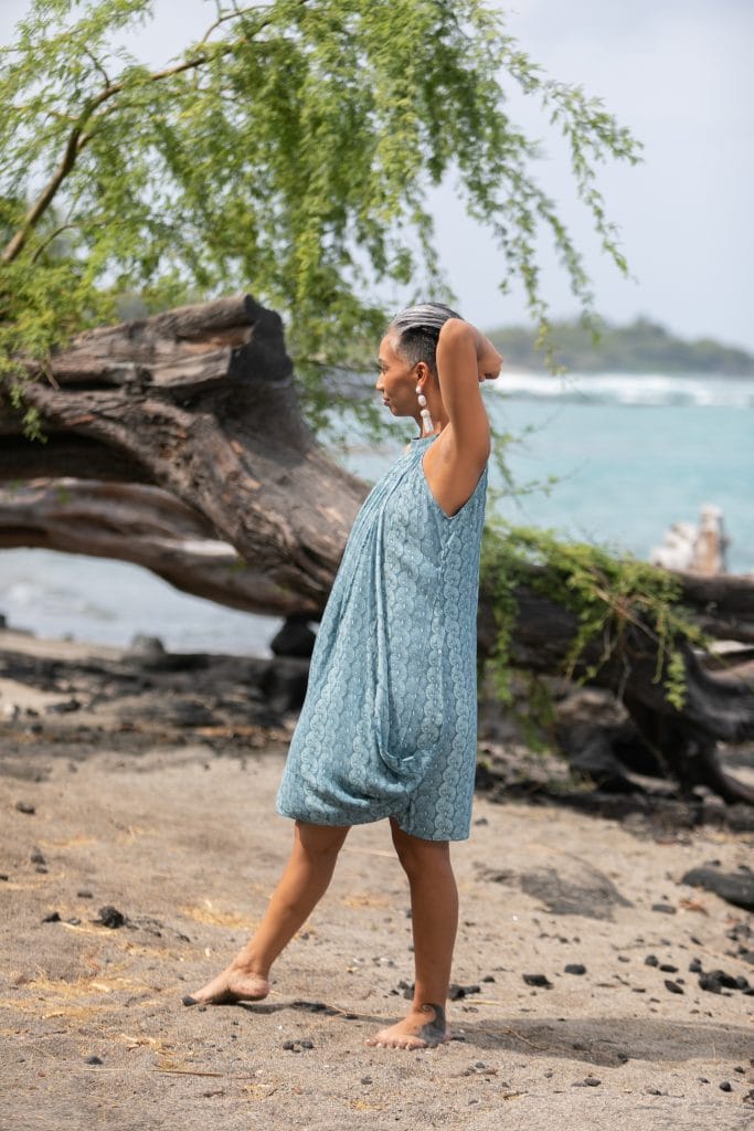 Female model wearing Kanoe Dress in a Lei Kupee Print and Real Teal/Blue Tint Color - Side View