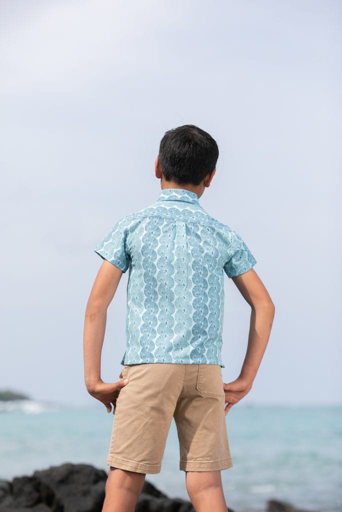 Boy model wearing Keiki S-S in a Lei Kupee Print and Blue Tint/Real Teal Color - Back View