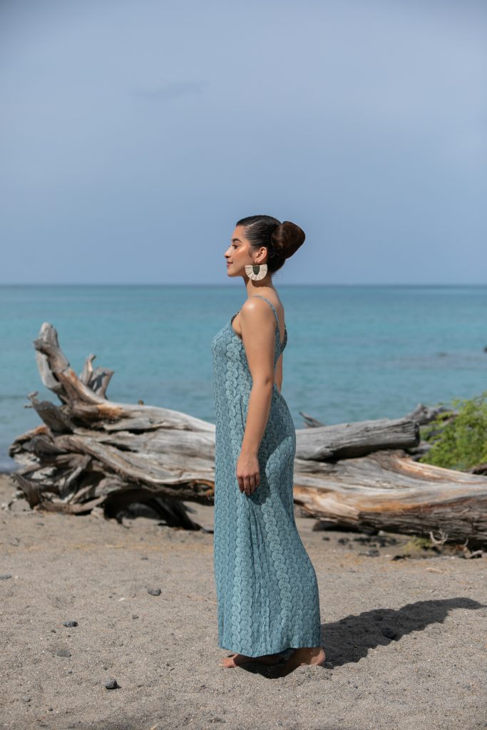 Female model wearing a Lanihau Jumpsuit in Lei Kupee Print and Real Teal/Blue Tint Color - Side View