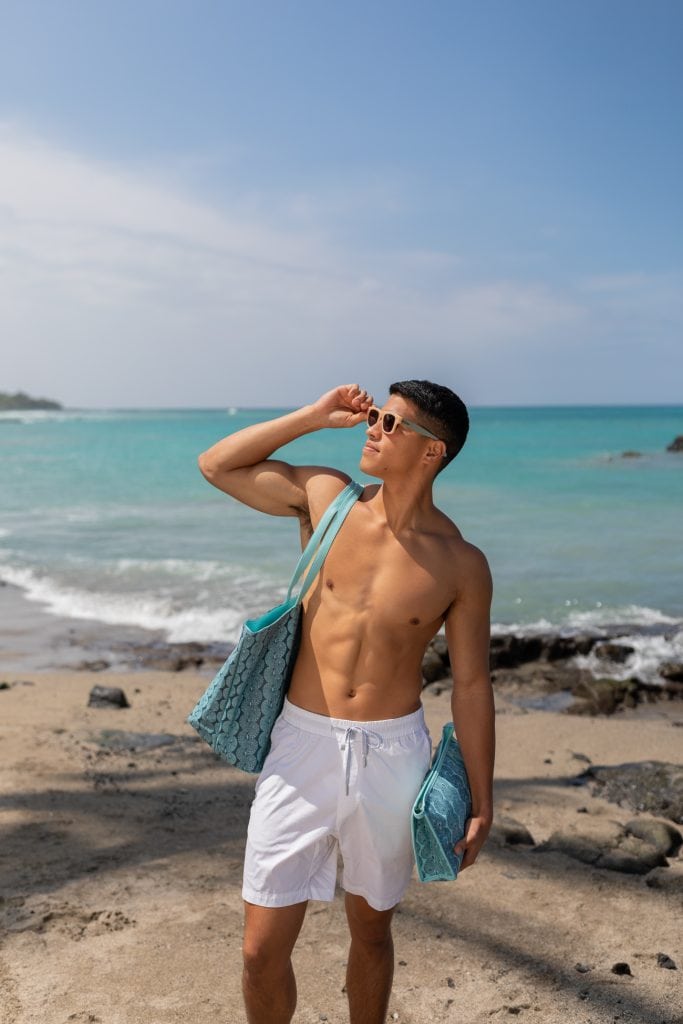 Male model holding Wailani Bag in a Lei Kupee Print and Blue Tint/Real Teal Color