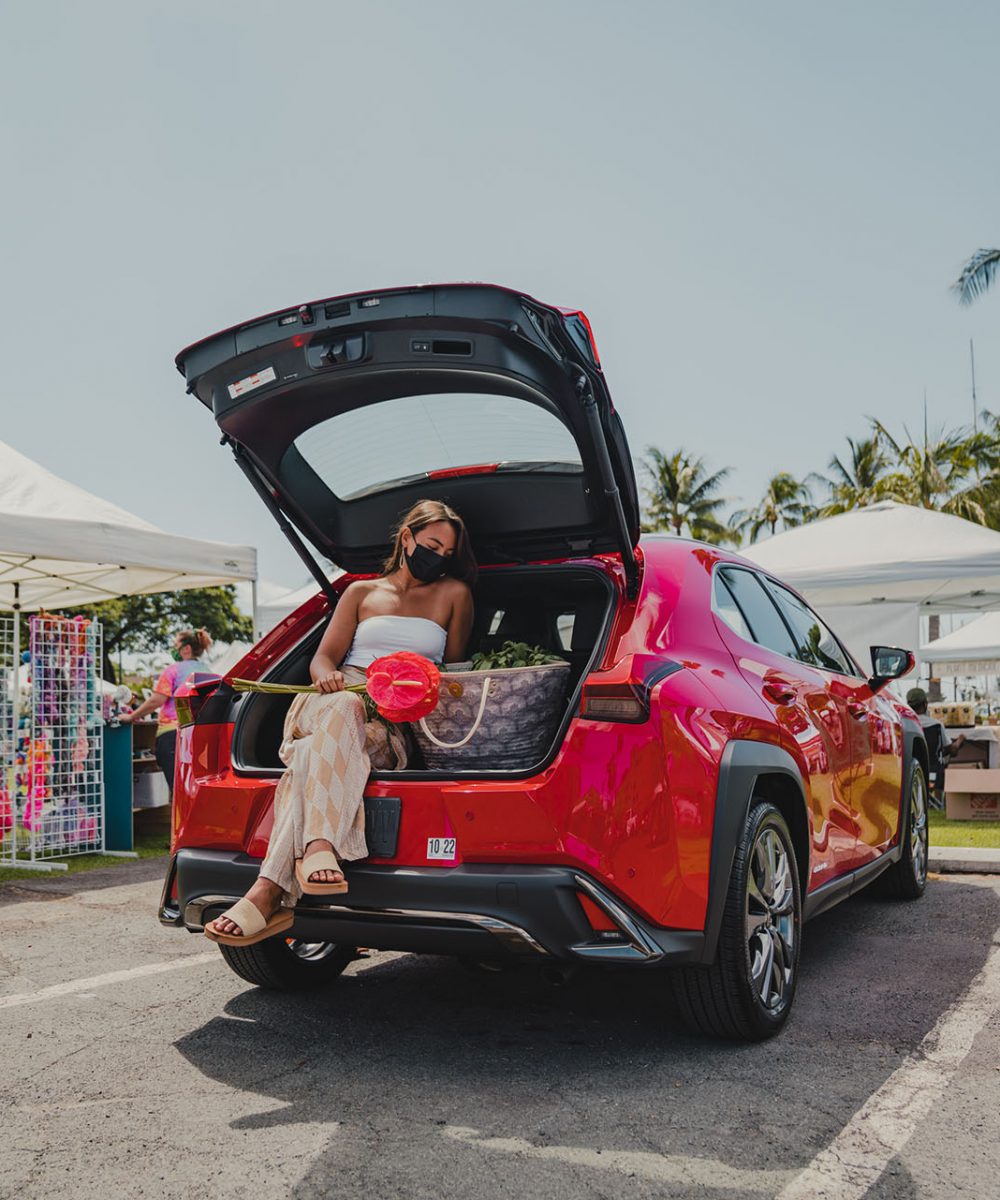 Female model sitting in a red lexus with Manaola products