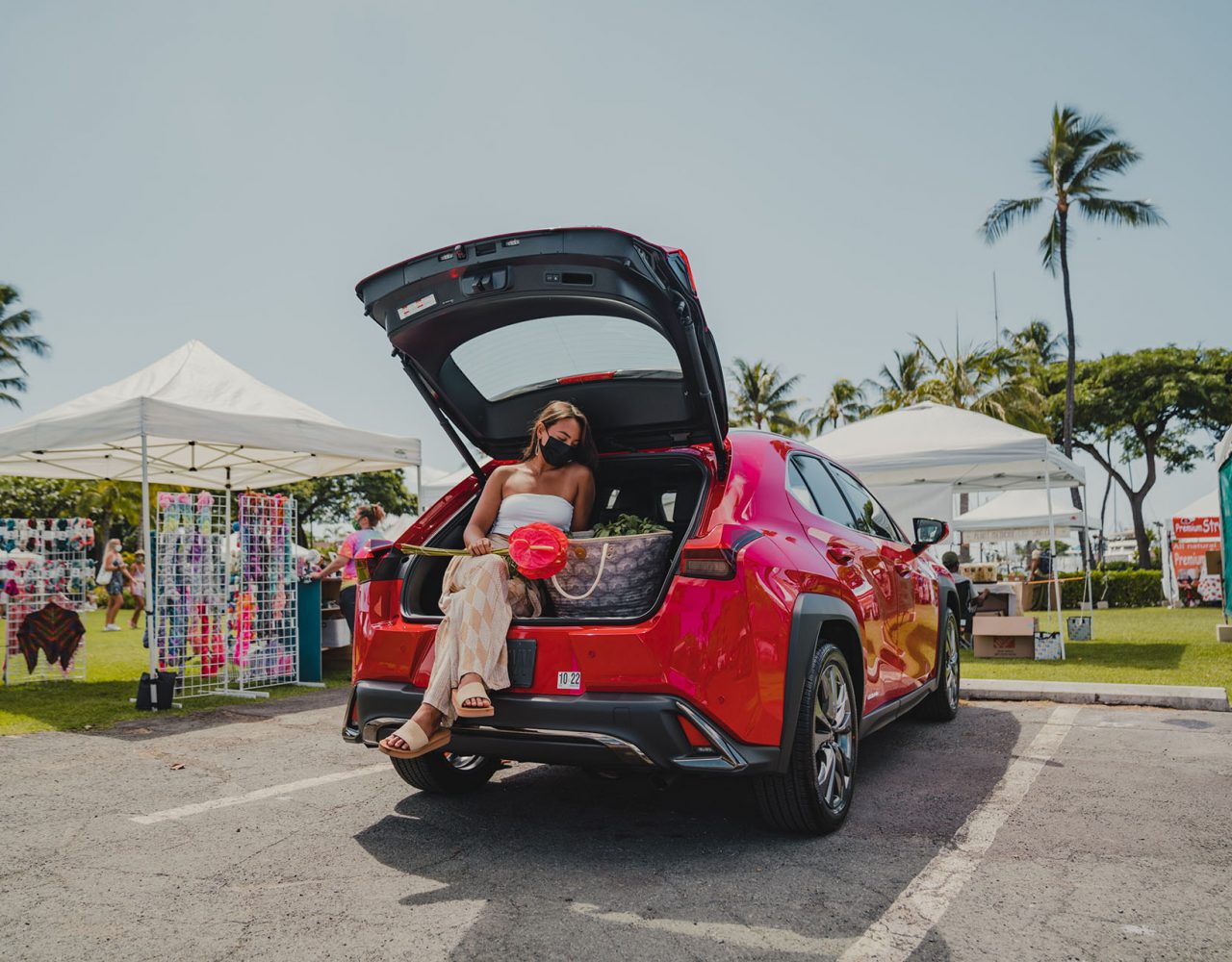 Female model sitting in a red lexus with Manaola products